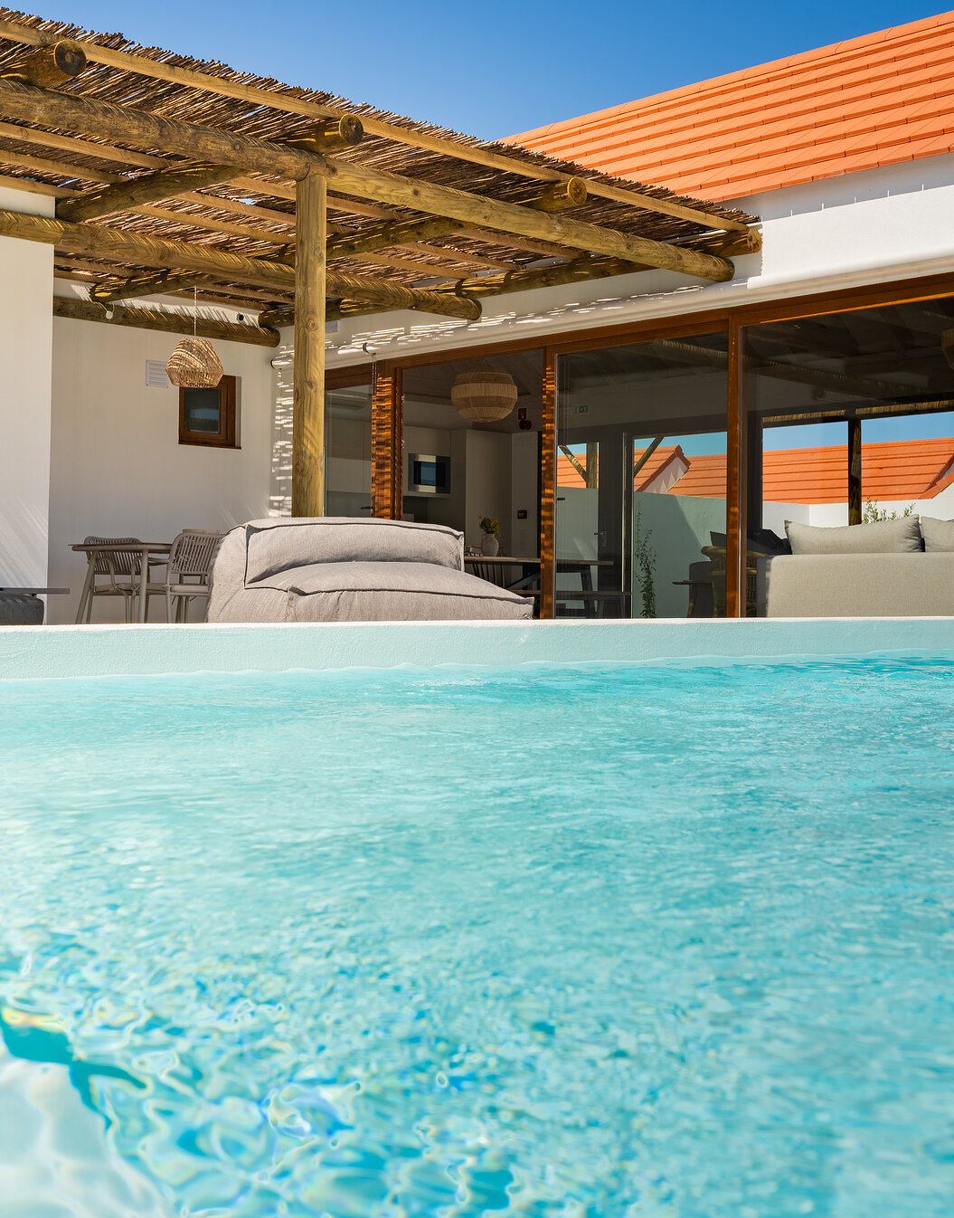 Espaço exterior de uma villa no Pestana Comporta Village Residences, com uma piscina de água azul cristalina e zona de estar
