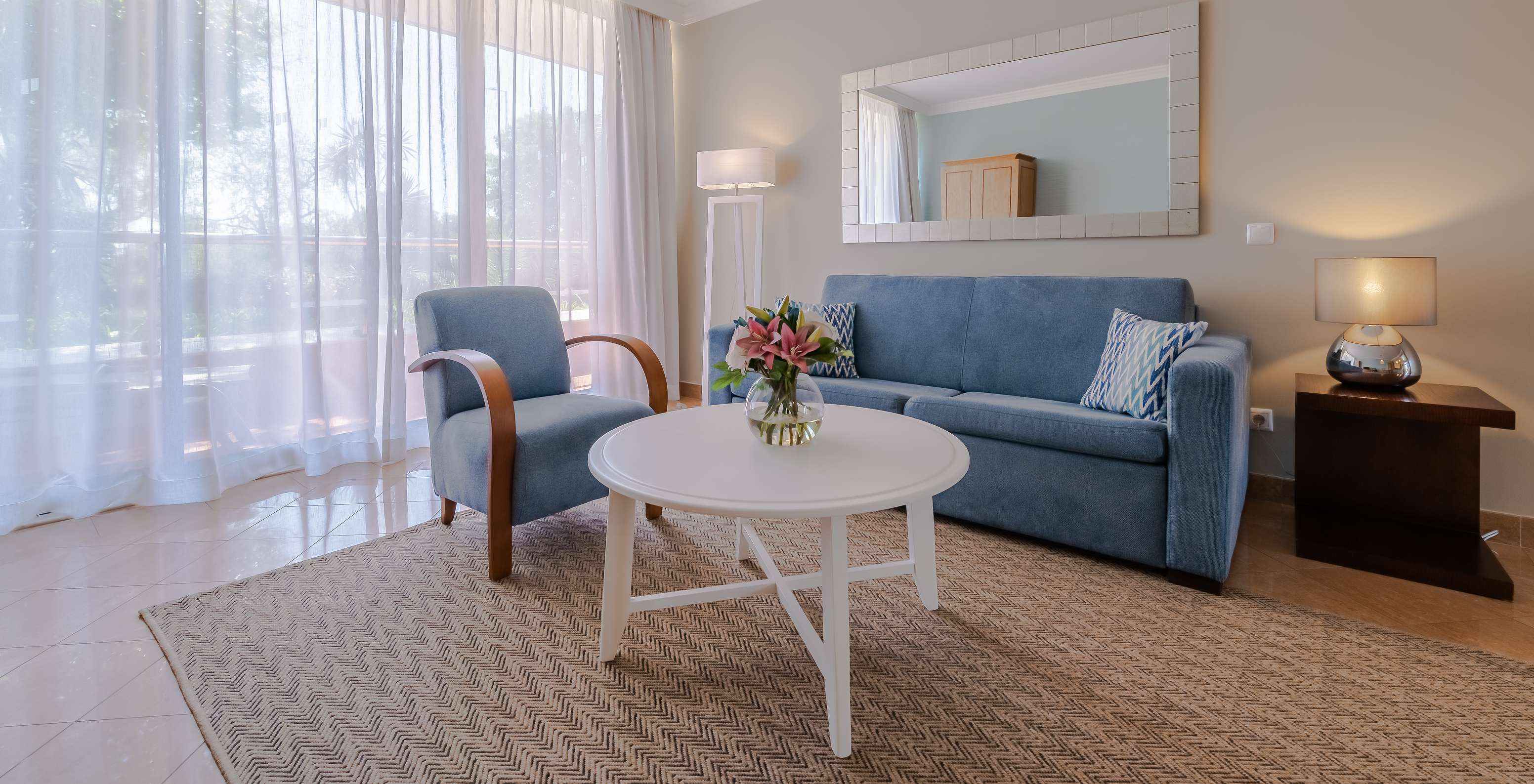O T1 - com 1 Quarto do Pestana Alvor Park tem uma sala de estar com um sofá e um cadeirão azuis