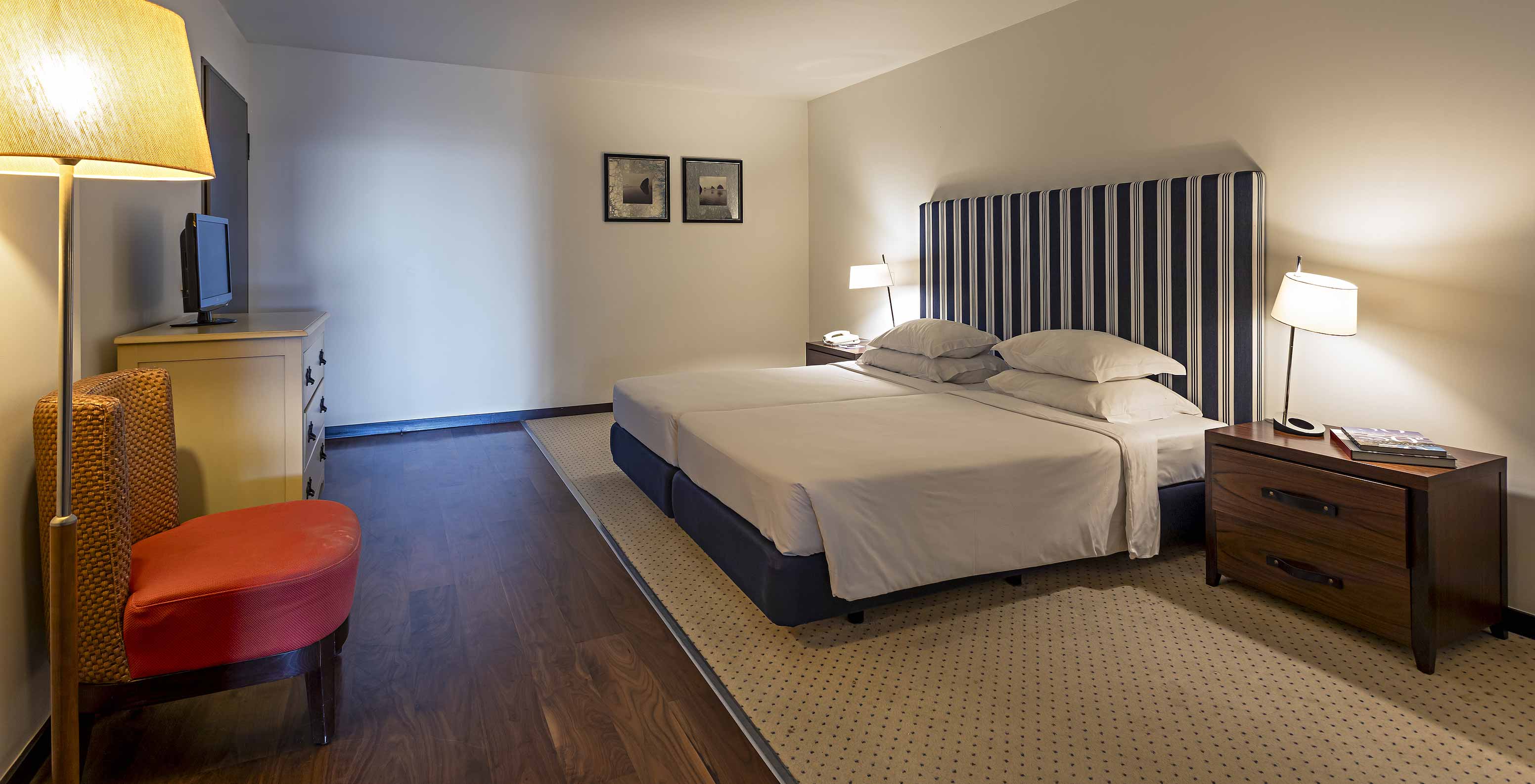 A Cliff Suite T2 do Pestana Alvor Praia tem um quarto grande com uma cama de casal, dois quadros, e uma cómoda com televisão