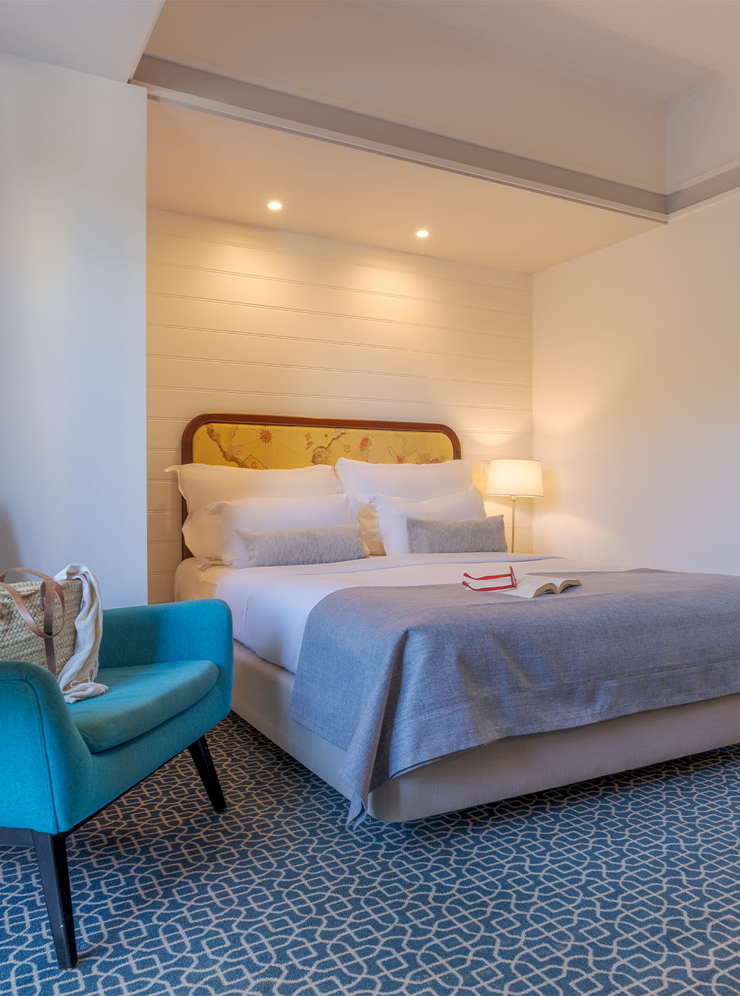 O Deluxe do Pestana Alvor Praia tem uma cama de casal, uma mesa com cadeirão azul, espelho e tapete com padrão geométrico