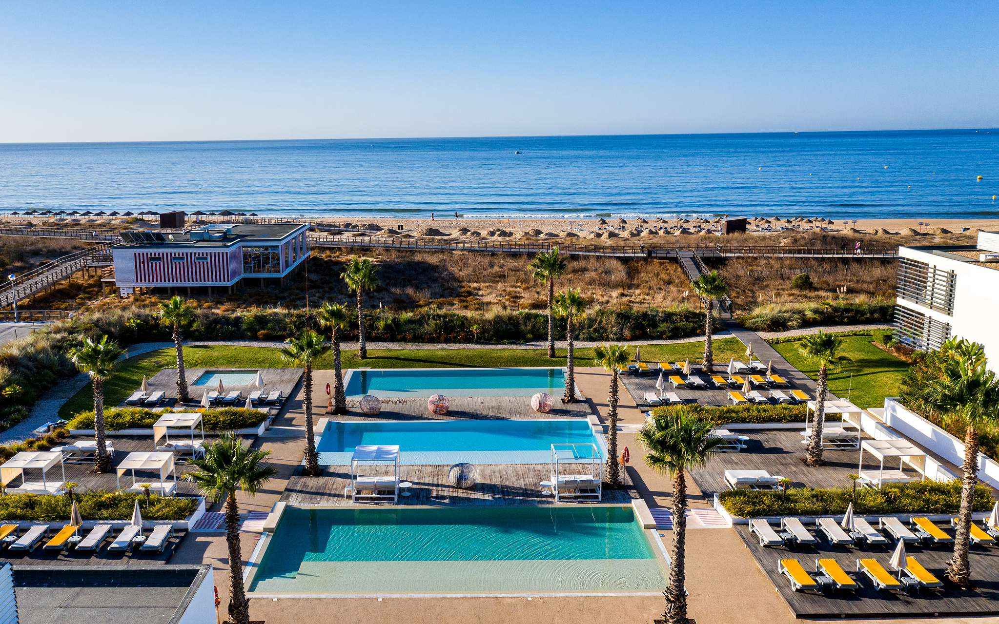 Zona exterior das piscinas e das espreguiçadeiras do Pestana Alvor South Beach, com acesso direto à praia