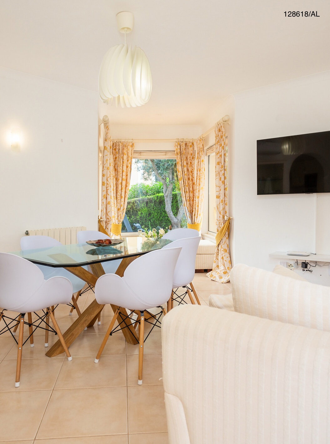 A Moradia V3 Superior do Pestana Carvoeiro Golfe tem uma sala de estar com uma mesa de vidro com cadeiras e uma televisão