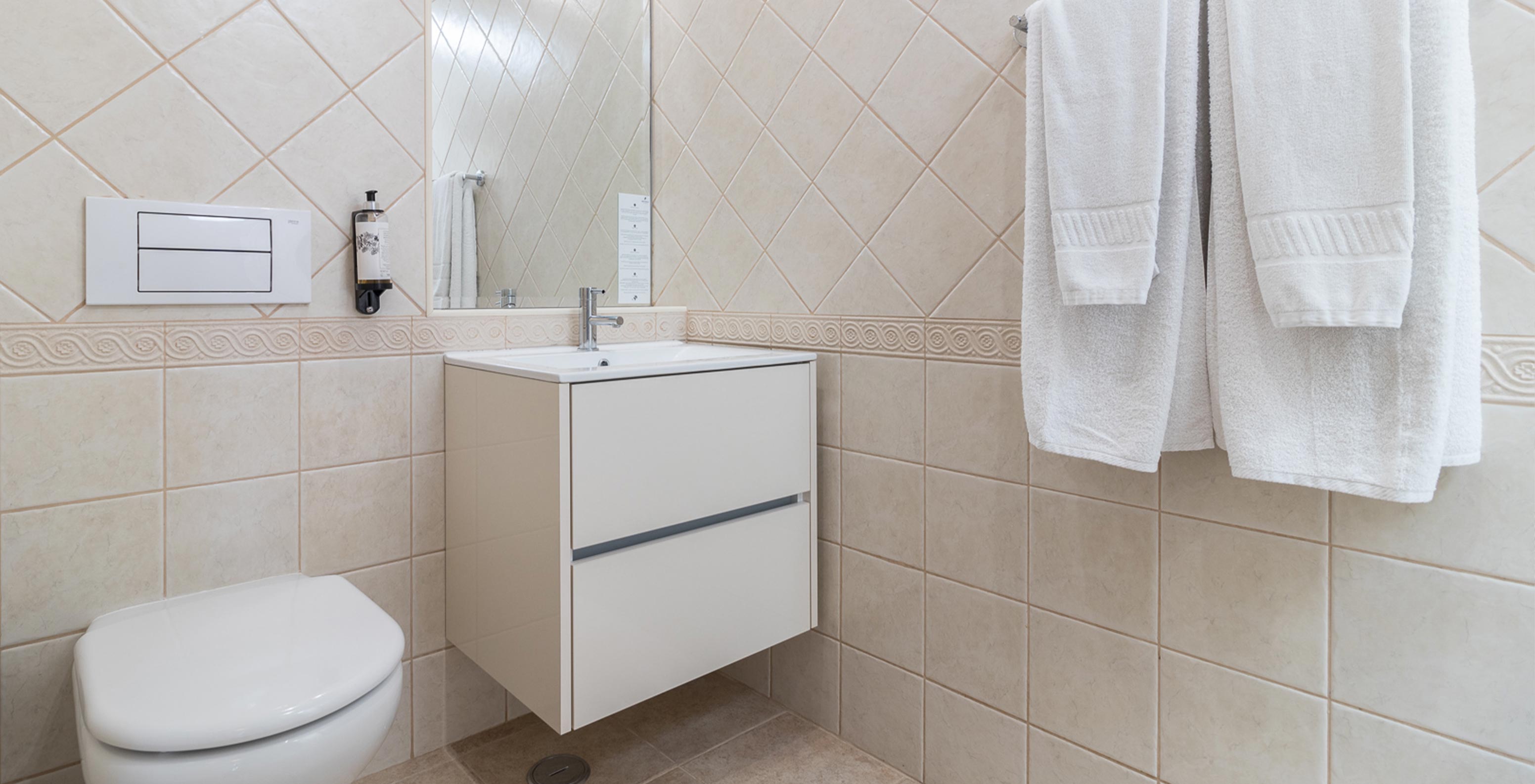 O Apartamento T2 do Pestana Gramacho Residences tem uma casa de banho elegante com toalhas brancas e luz natural suave