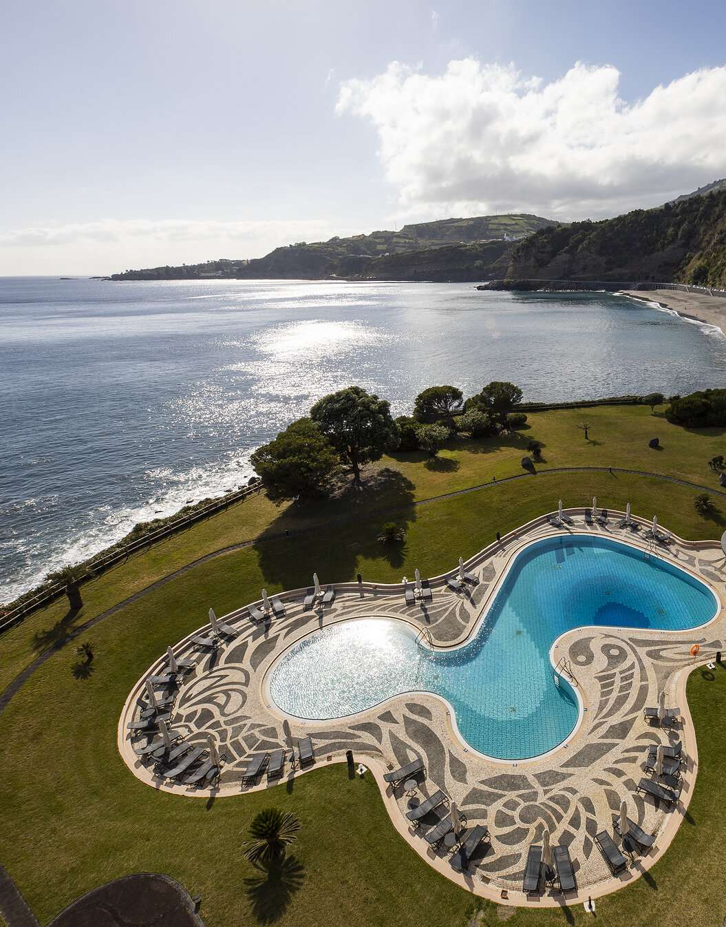 Piscina com vista para o mar e praia junto ao Pestana Bahia Praia em São Miguel num dia parcialmente nublado
