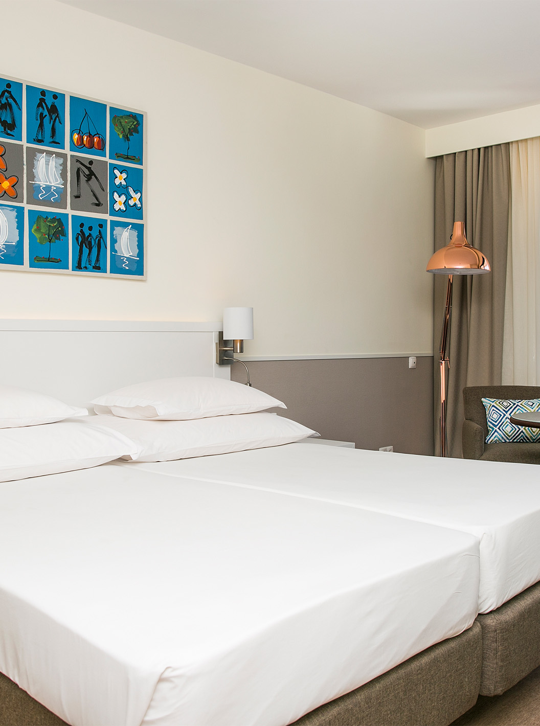 O quarto Deluxe Vista Mar do Pestana Cascais conta com duas camas individuais, camdeeiros, e um cadeirão com mesa