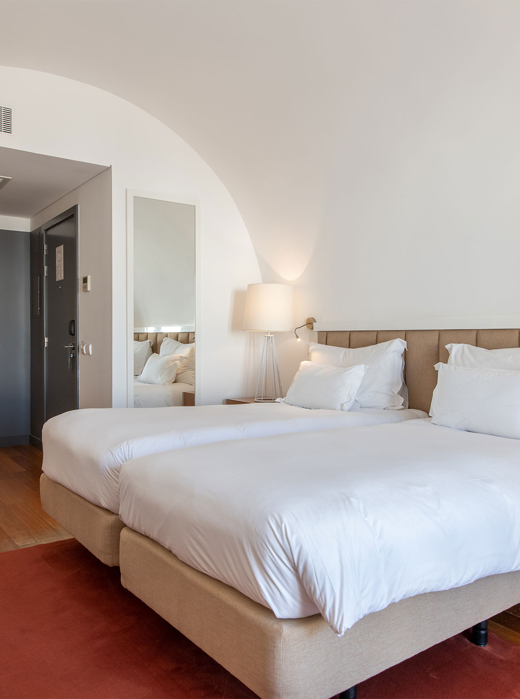 O Quarto Clássico do Pestana Cidadela Cascais tem duas camas individuais, um tapete vermelho e um espelho grande