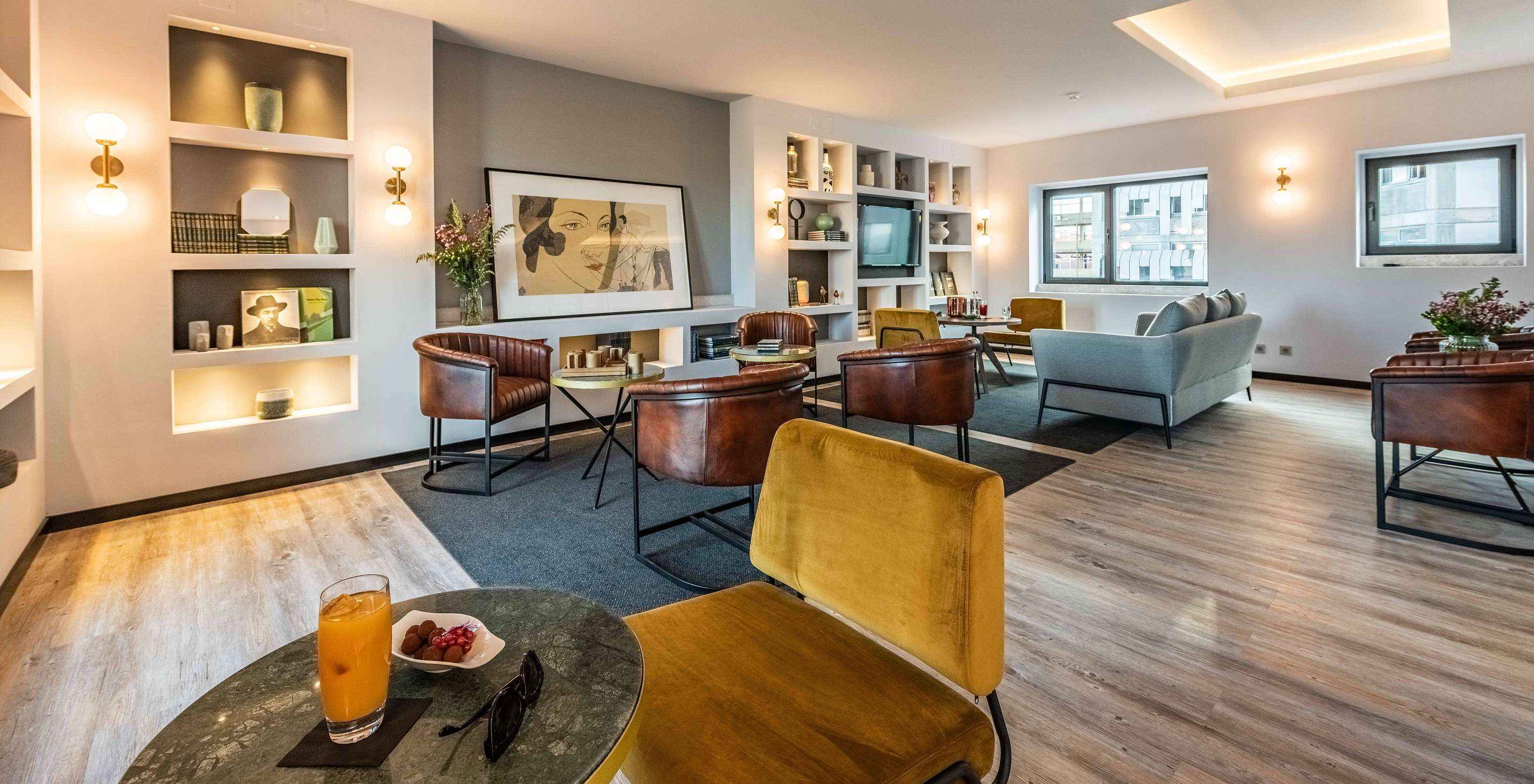 Lounge com sofás, cadeiras, mesas, quadros, televisão, tapetes e objetos de decoração com janelas com vista para a cidade