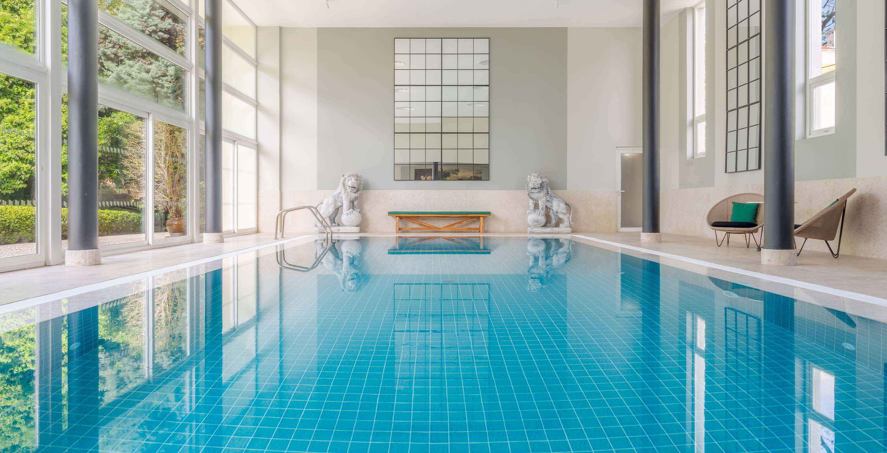 Piscina interior do Palace Lisboa, Hotel num Palácio em Lisboa, com Piscinas e Spa com luz natural e duas esculturas de leões