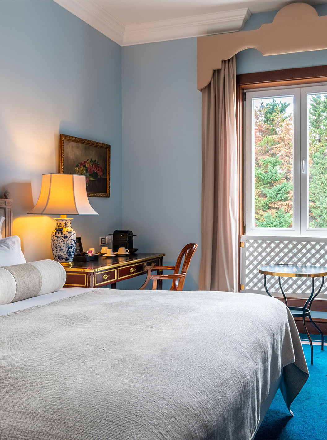 O Deluxe do Pestana Palace Lisboa tem uma cama de casal, uma secretária, uma janela com uma grade decorativa e carpete azul