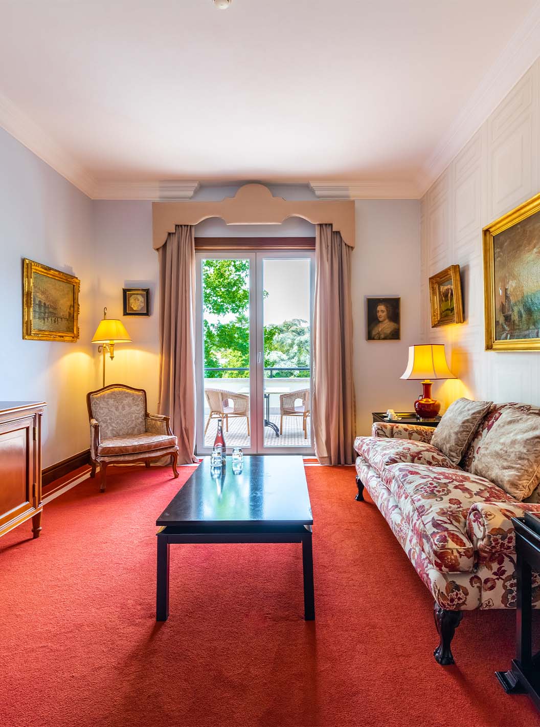 A Suite Collection do Pestana Palace Lisboa tem uma sala com sofá, televisão, janela com acesso à varanda e quadros na parede