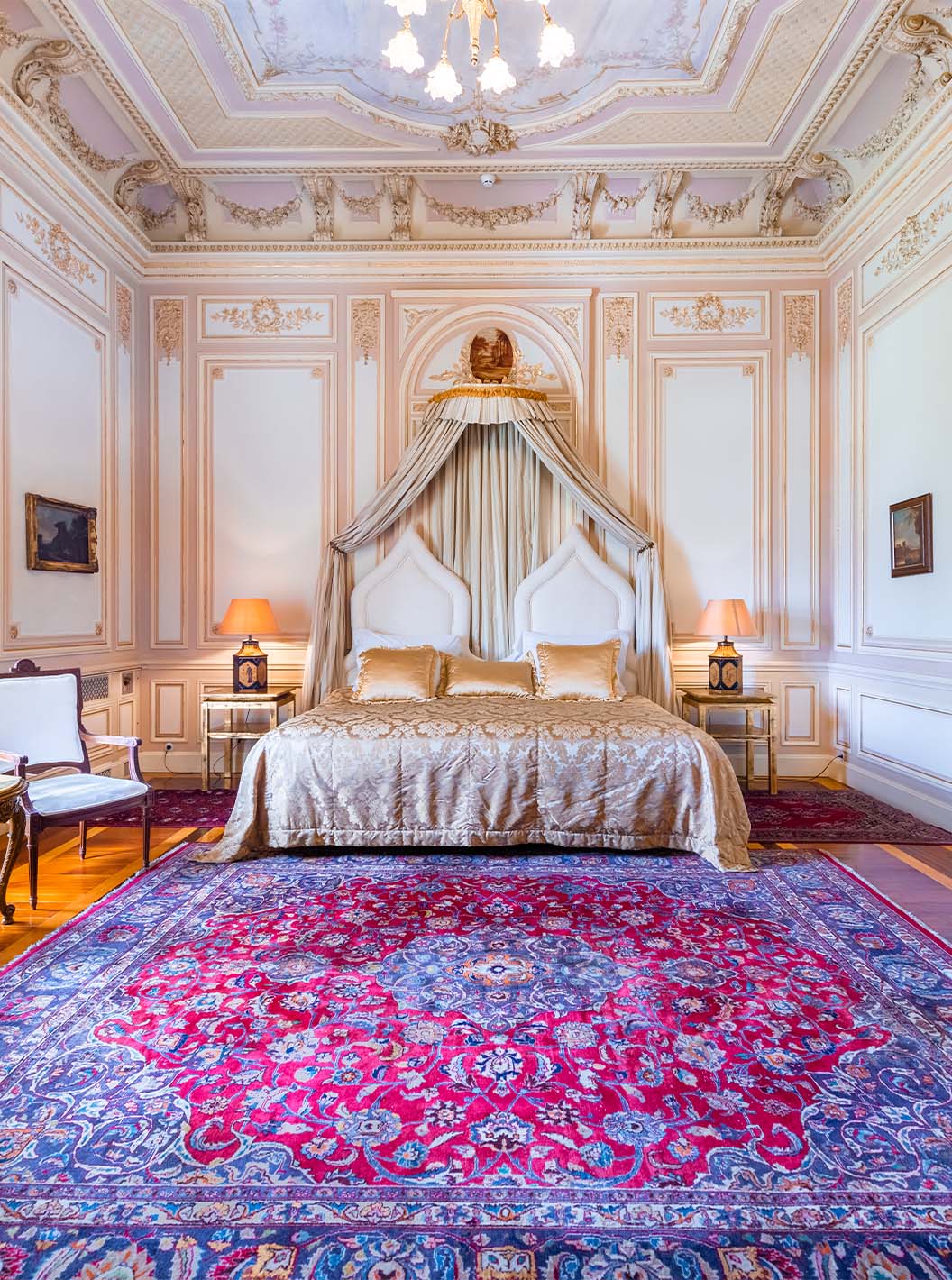 A Suite D. Carlos do Pestana Palace Lisboa tem um quarto luxuoso com cama de casal e teto com detalhes ornamentados