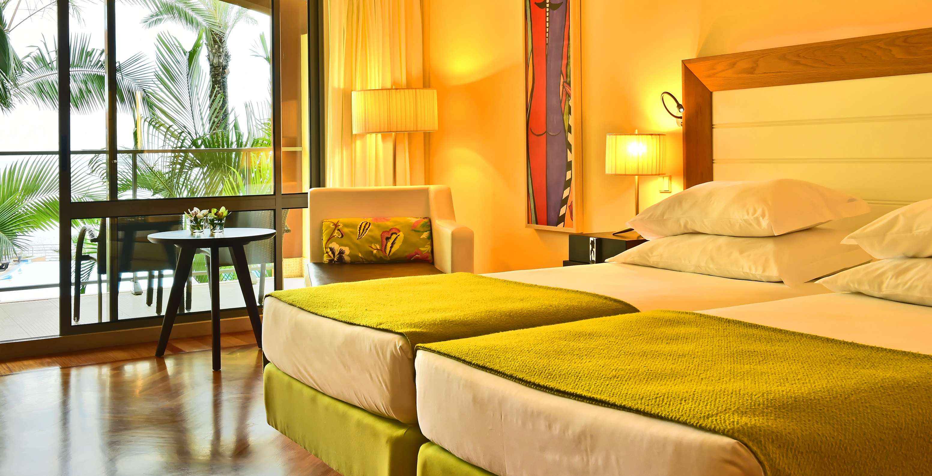 O Clássico Vista Piscina do Pestana Promenade tem duas camas com uma colcha verde e uma janela grande para a varanda