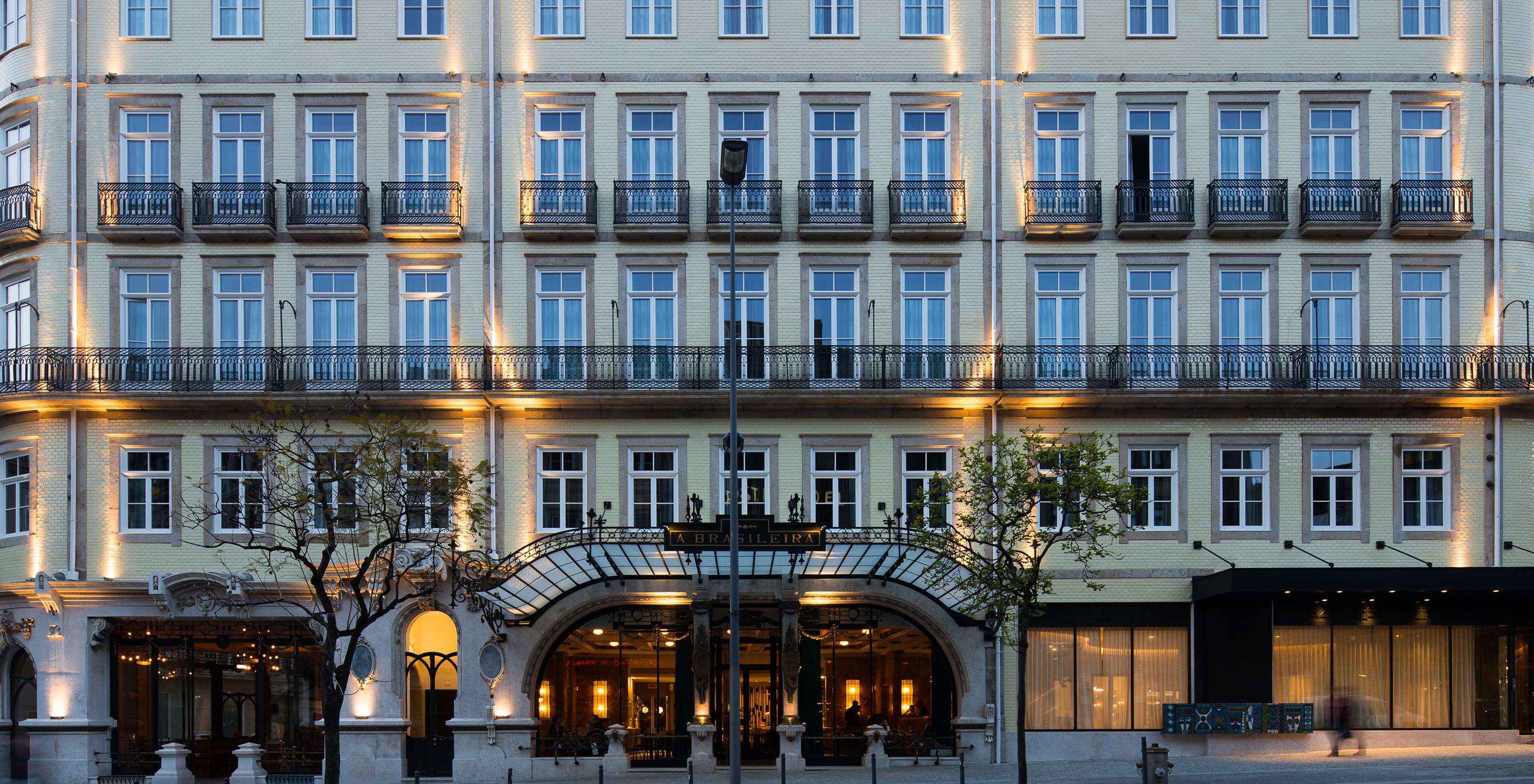 A fachada iluminada do hotel Pestana Porto - A Brasileira exibe uma arquitetura imponente com detalhes clássicos