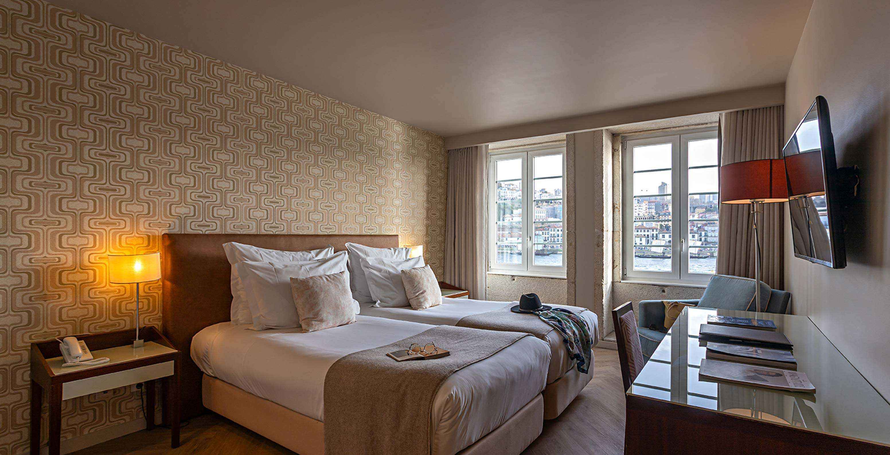 O Vintage River View do Pestana Vintage Porto tem duas camas individuais, papel de parede em tons areia e duas janelas