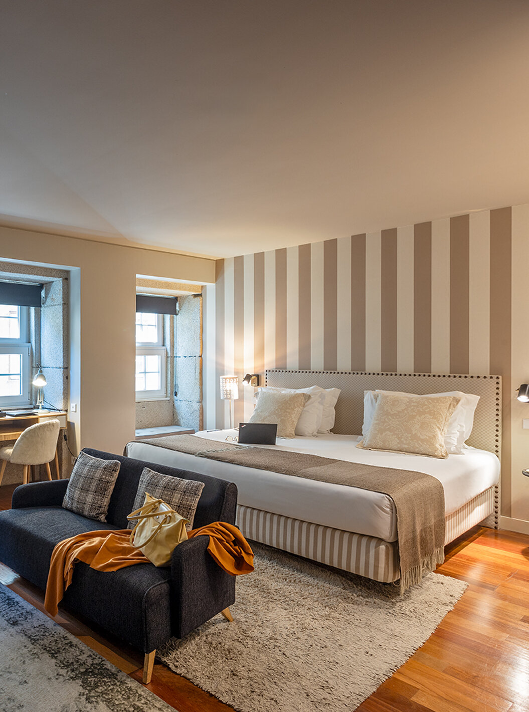 A Heritage Suite do Pestana Vintage Porto tem uma cama de casal, dois sofás sobre tapetes e várias janelas