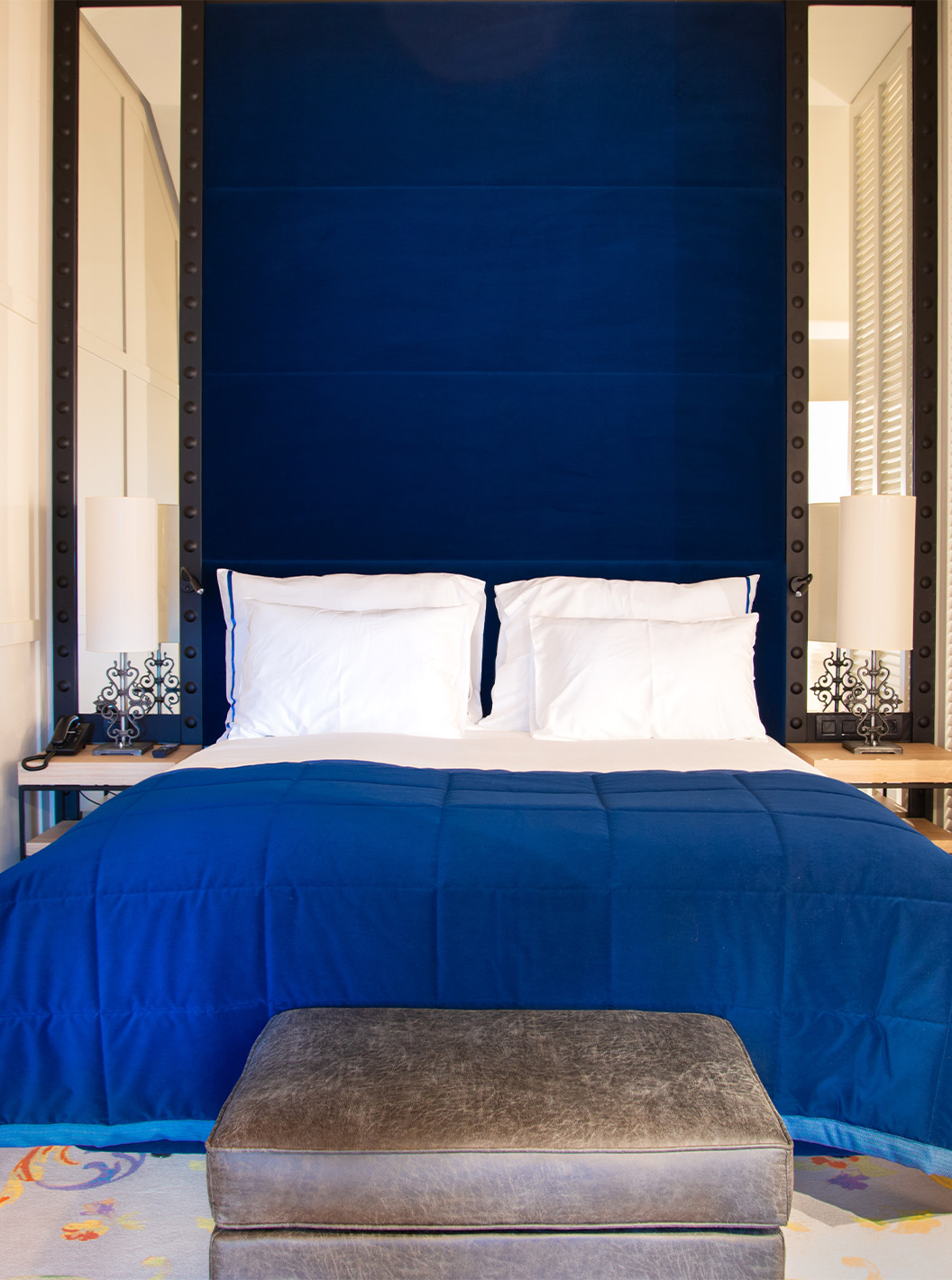 O Loft do Pestana Plaza Mayor Madrid tem uma cama de casal com uma cabeceira azul e espelhos, e uma televisão na parede