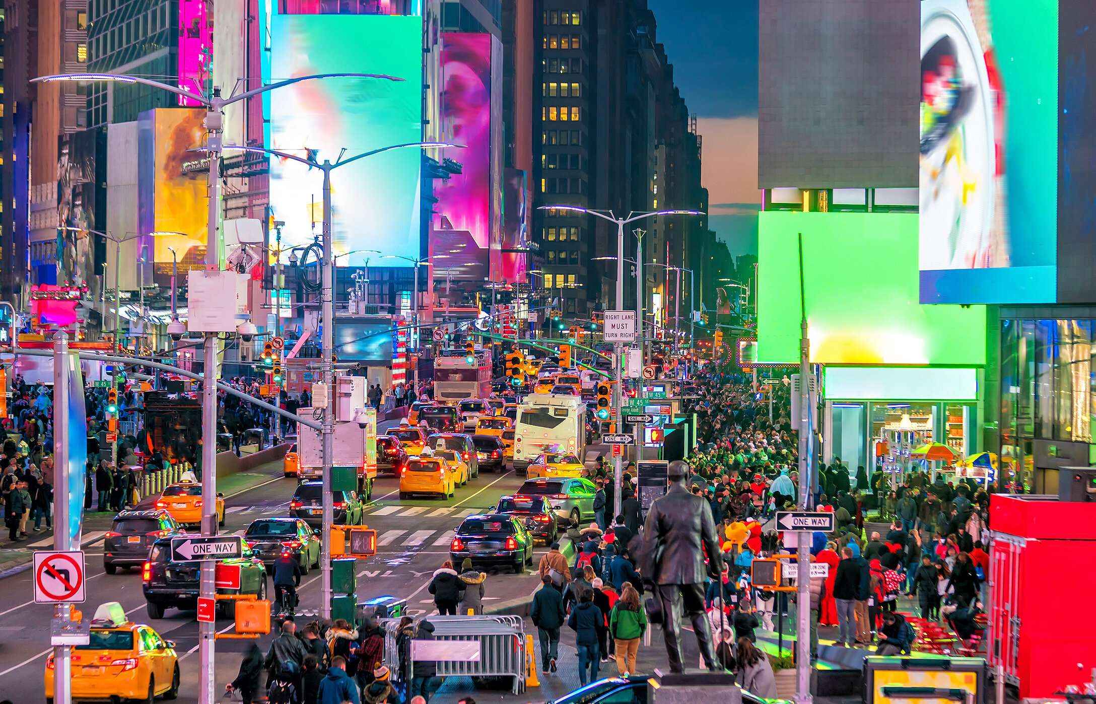 Vista panorâmica de Times Square, um cruzamento com painéis luminosos de publicidade, multidões de turistas e arranha-céus