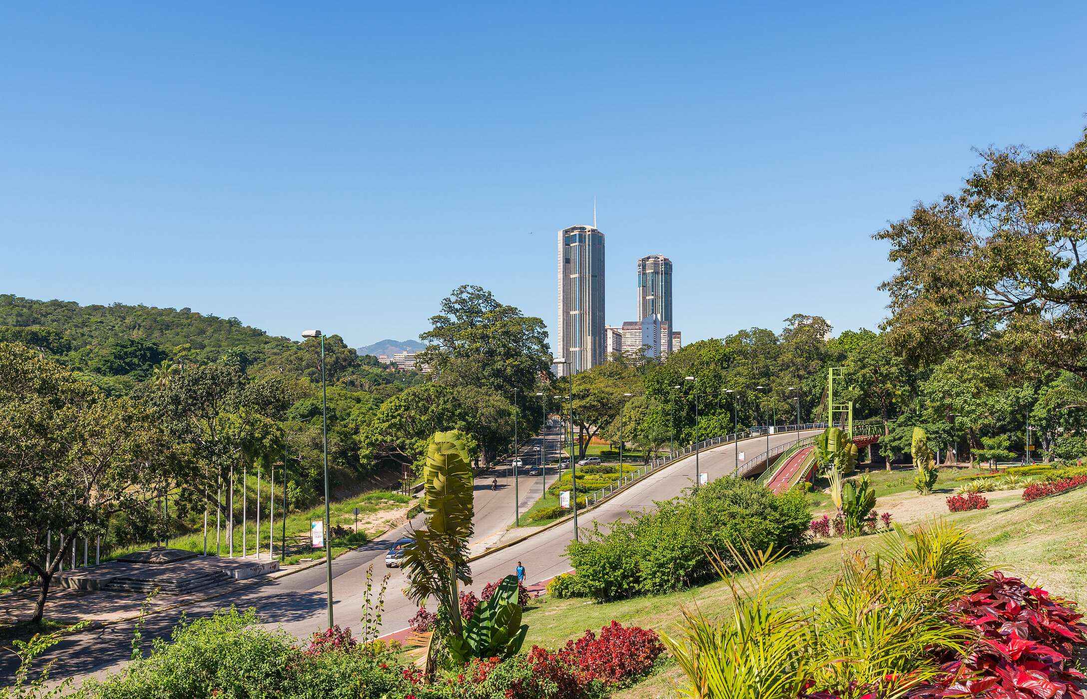Paisagem urbana de Caracas, com vários espaços verdes e floridos, com as torres gémeas de El Silencio no fundo