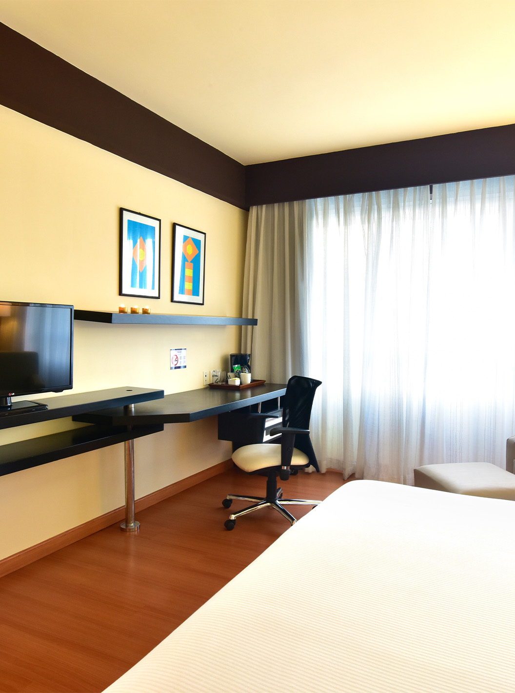 O Twin Superior do Pestana Caracas tem uma televisão no fundo da cama, uma poltrona, uma secretária e uma janela