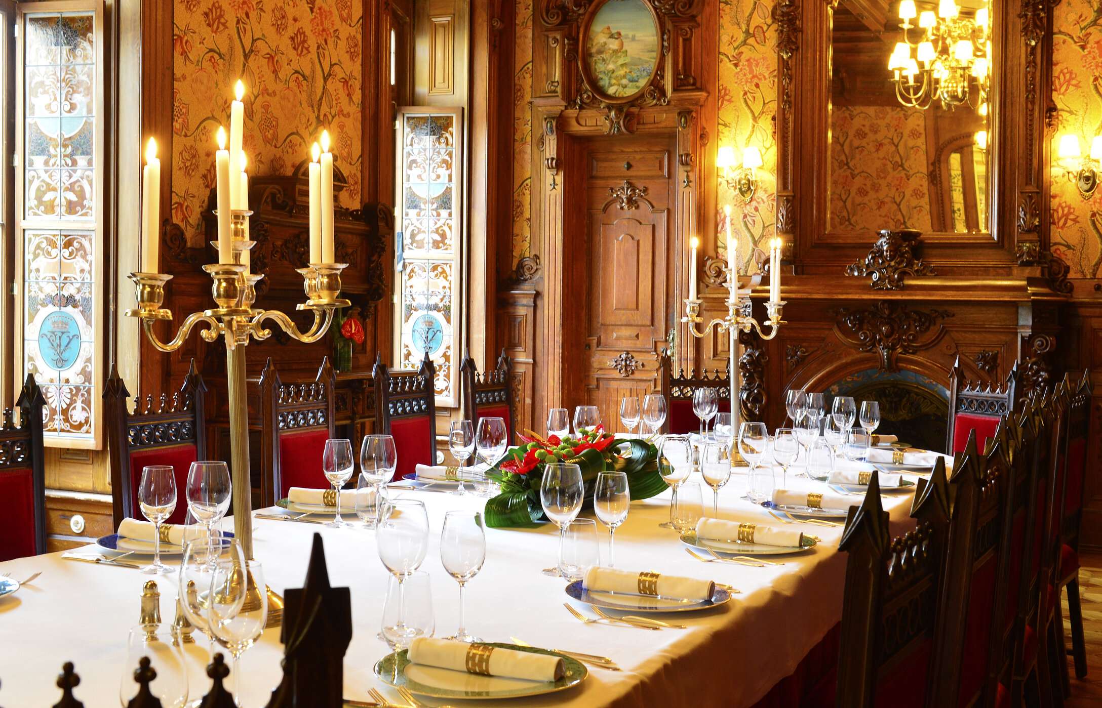 Casamento em sala imponente com decoração elegante, com mesa comprida com arranjos florais e paredes com madeira trabalhada