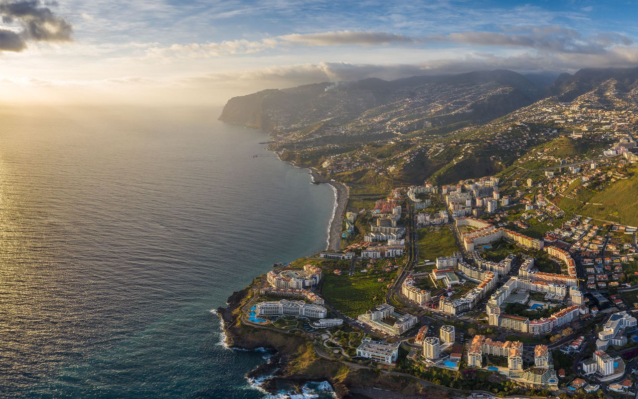 Luchtzicht op de stad Funchal op Madeira, met een haven met boten, dichtbebouwde stedelijke gebieden en bergen op de achtergrond