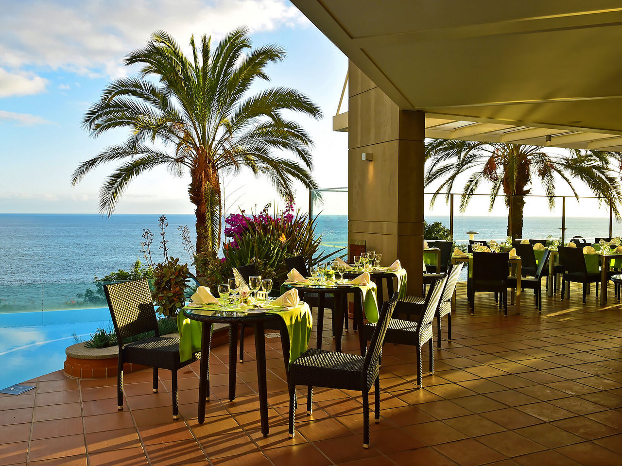 Het restaurant The Deck, van het hotel aan zee in Funchal, heeft verschillende tafels met uitzicht op het zwembad en de zee
