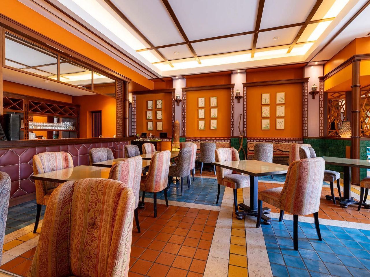 Restaurant Arab Magrebe van het 5-sterrenresort op Porto Santo heeft warme tinten, vierkante tafels en gestoffeerde stoelen.