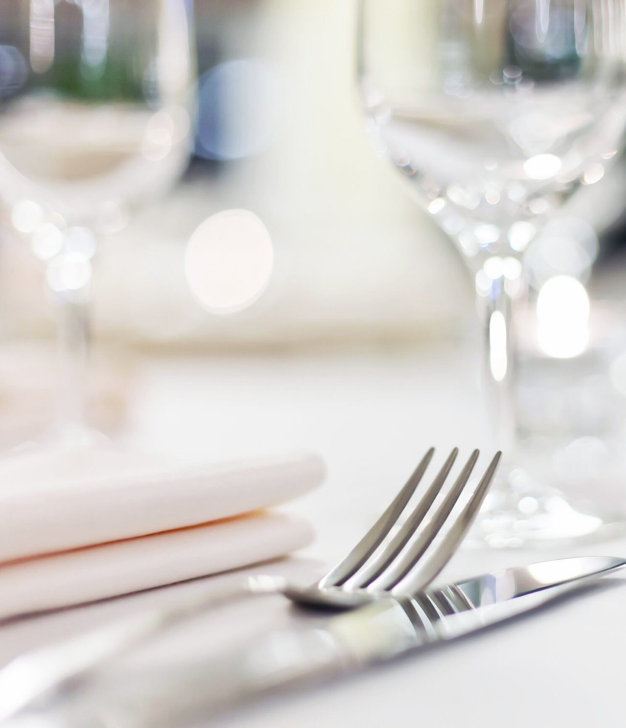 Elegant table set with silver cutlery, cloth napkin, and glassware, in a well-lit setting