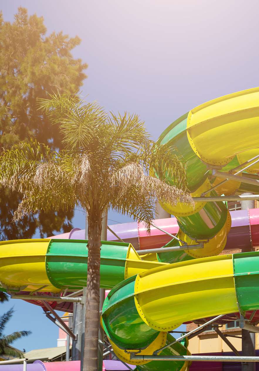 Aquashow in the Algarve, a water park with palm trees and colorful slides in yellow, green, pink and lilac