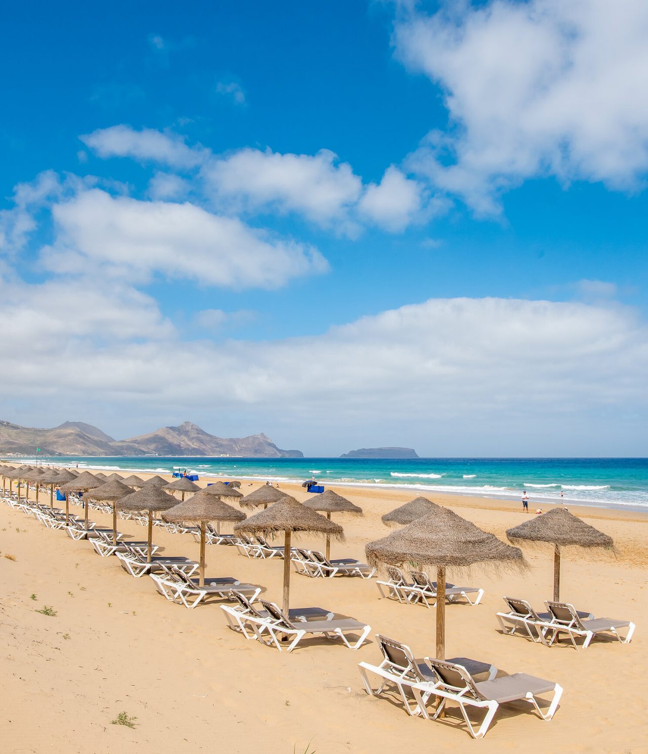 Porto Santo beach, with several sun loungers and umbrellas, turquoise blue sea, and golden sand