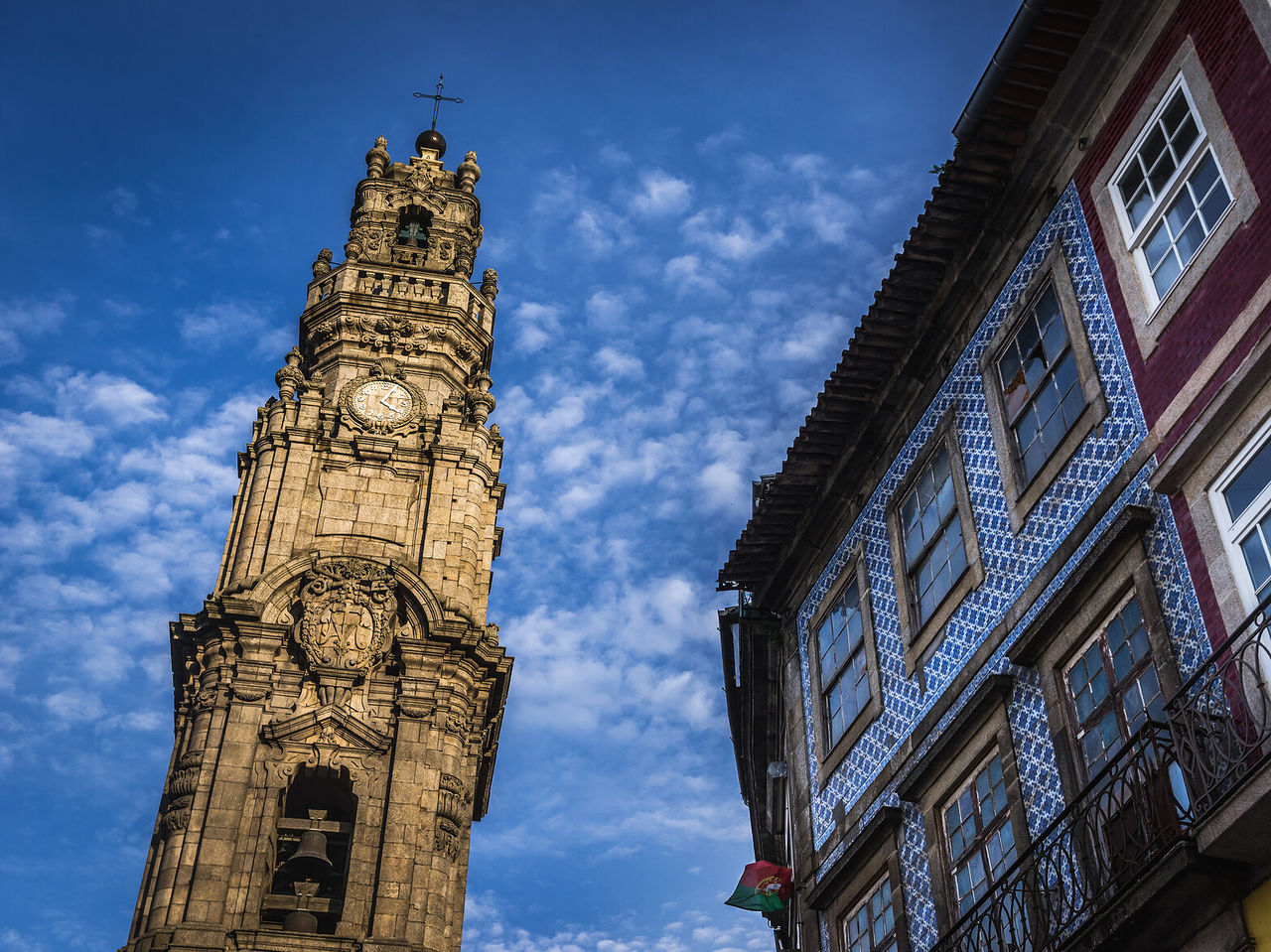 Imposing Clerigos Tower standing out against the blue sky, while a neighboring building displays typical architecture