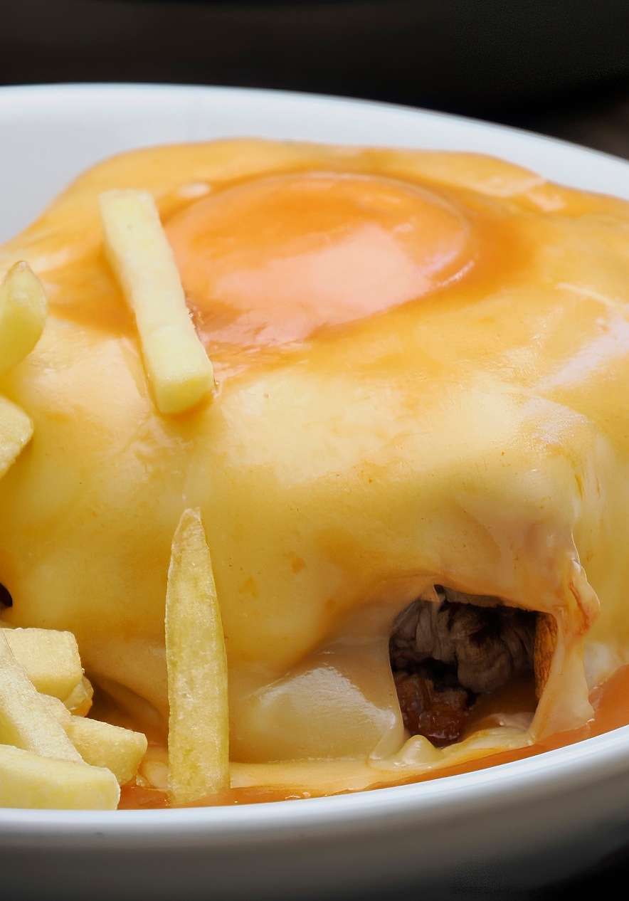 Francesinha is one of the most famous dishes in Porto with cheese egg spicy sauce and fries
