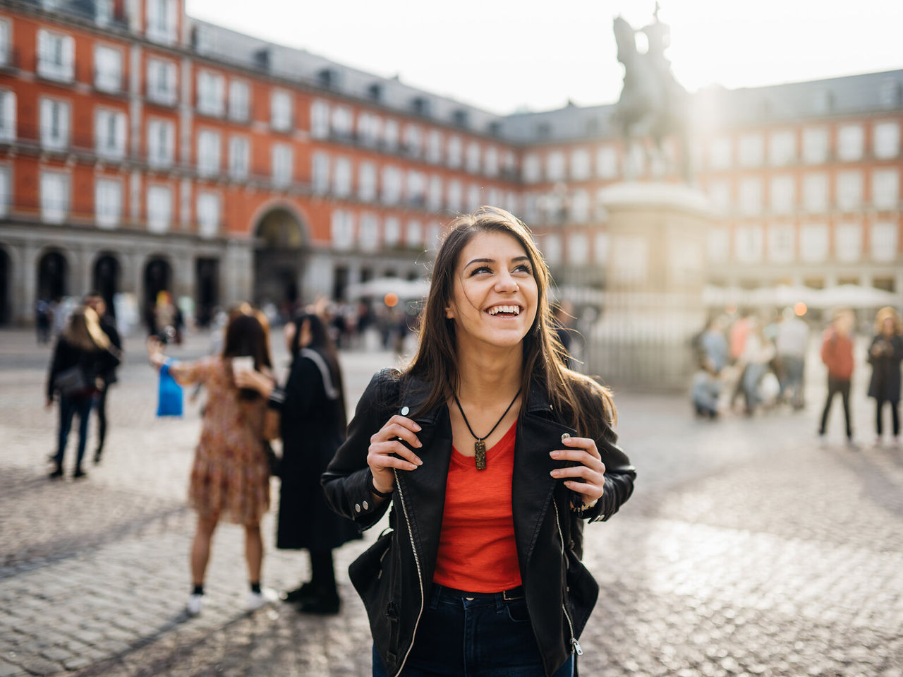 Happy girl with a backpack strolling through Plaza Mayor, in Madrid's historic center