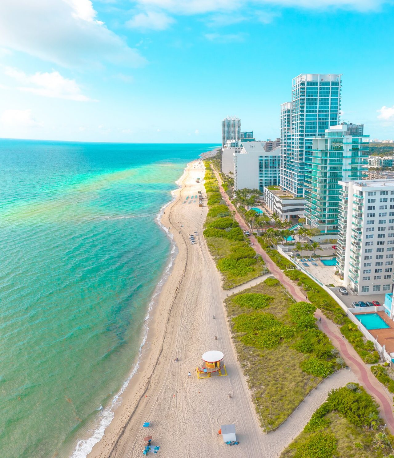 Miami Beach, Florida, with white sand, turquoise seawater, and people swimming and sunbathing on chairs