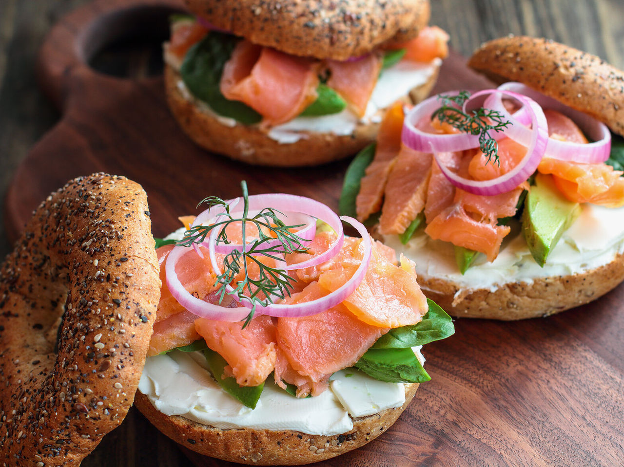 Typical American bagel with salmon, cream cheese, avocado, spinach, and red onion