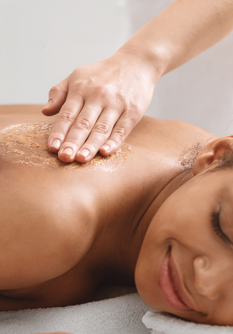 A client receiving a massage at Pestana Magic Spa, where the professional gently applies an exfoliant to the back
